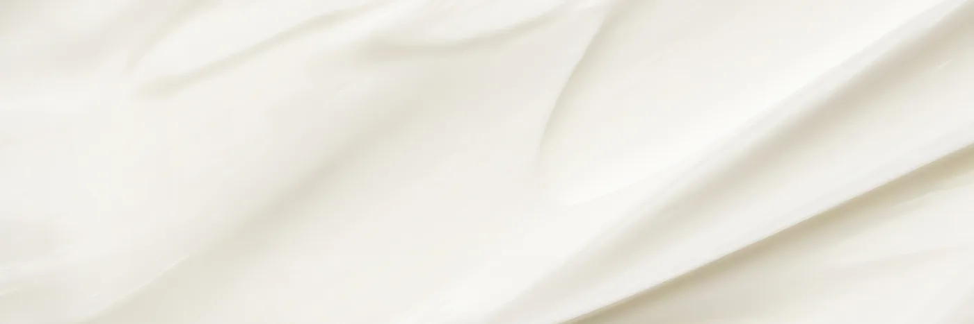 A close macro of smooth white cream, the soft lactonic texture that milk perfumes are built to smell like.
